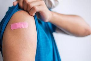 homme montrant un bandage après avoir reçu le vaccin covid 19. vaccination, immunité collective, effet secondaire, dose de rappel, passeport vaccin et pandémie de coronavirus photo