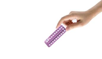 main de femme prenant des pilules contraceptives. femme adulte asiatique tenant un paquet de pilules contraceptives isolé sur fond blanc avec un tracé de détourage. choisir la planification familiale avec le concept de pilules contraceptives photo
