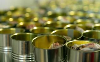 usine de conserves de poisson. industrie alimentaire. de nombreuses boîtes de sardines sur un tapis roulant. sardines en conserve à l'usine alimentaire. chaîne de production agro-alimentaire. l'industrie agroalimentaire. l'industrie des boîtes de conserve. photo