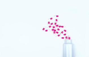 pilules de capsule antibiotique rose-blanc réparties dans une bouteille de médicament en plastique blanc. concept de résistance aux antibiotiques. utilisation de médicaments antibiotiques. soins de santé mondiaux. fond de pharmacie. industrie pharmaceutique. photo