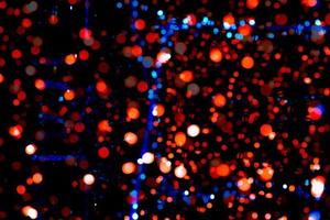 lumière de décoration de noël et bonne année. fond bokeh de couleur rouge, bleu, orange avec un beau motif. lumière de noël défocalisée dans la nuit de la fête. fond de bokeh de vacances de noël. photo