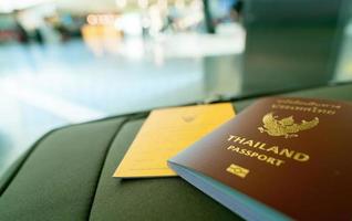 passeport thaïlandais et passeport vaccinal sur les bagages sur fond flou de touriste à l'aéroport. certificat de vaccination pour voyager pendant l'épidémie de coronavirus. les mots thaïlandais sont un passeport thaïlandais. photo
