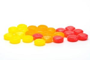 pastilles médicales pour soulager la toux, les maux de gorge et les irritations de la gorge isolées sur fond blanc. la toux et le rhume tombent. pastille contre la toux colorée. bonbons ronds rouges, oranges et jaunes. photo