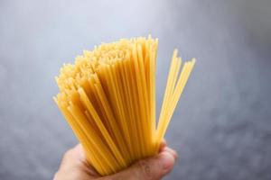Man holding raw spaghetti pâtes italiennes spaghettis non cuits jaune long prêt à cuisiner dans le restaurant cuisine italienne et menu photo