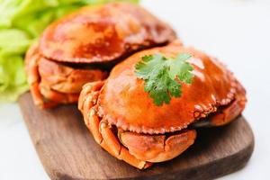 crabe de pierre de fruits de mer frais - crabe cuit à la vapeur ou bouilli avec salade de légumes sur planche de bois sur fond blanc photo