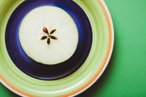 la moitié d'une pomme sur une assiette colorée. photo