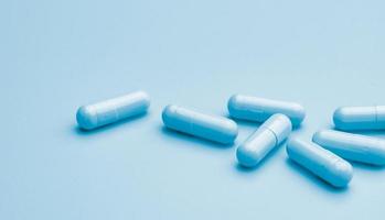 pilules de capsule bleues sur fond bleu. bannière de pharmacie en ligne. groupe de gélules. industrie pharmaceutique. développement de médicaments et recherche de nouveaux médicaments pour le traitement des maladies infectieuses émergentes. photo