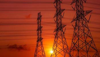 pylône électrique haute tension et fil électrique avec ciel coucher de soleil. poteaux électriques. concept de puissance et d'énergie. tour de réseau haute tension avec câble métallique. beau ciel coucher de soleil rouge-orange. Infrastructure. photo