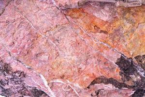 fond de texture de pierre avec motif unique. texture de roche rose, rouge, noire. fond abstrait de la surface de la roche. fond de pierre naturelle. sol en pierre brute violette. texture de roche grunge et rouille. photo