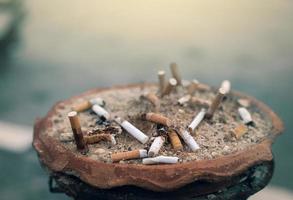 cendrier plein de mégots de cigarettes. cigarette usagée dans le cendrier. déchets de filtre de cigarette sale dans le cendrier en argile. déchet toxique. arrêter de fumer ou cesser de fumer et concept de déclenchement du cancer du poumon. produit du tabac. photo