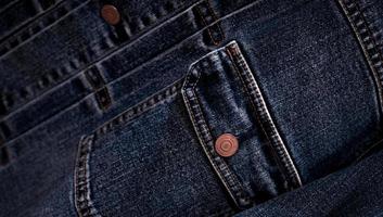 mise au point sélective sur la poche de la veste en jean denim dans la boutique de vêtements. poche de veste en jean et texture de bouton. industrie textile. mode jeans et concept de shopping. notion de vêtements. veste en jean à vendre. photo