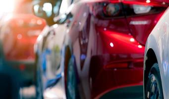 voiture rouge et blanche floue garée dans une rangée. industrie automobile. concept de marché mondial du véhicule électrique. flou photo gros plan de la nouvelle voiture rouge brillante. bannière pour les entreprises d'entretien et de nettoyage automobiles