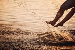 couple éclaboussant leurs pieds dans l'eau au coucher du soleil photo