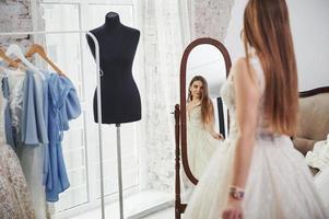 concentré sur le miroir. le processus d'essayage de la robe dans l'atelier de vêtements fabriqués à la main photo