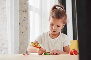 utiliser un bâtonnet de bonbons artificiels pour créer de nouvelles choses. enfants jouant avec de la pâte à modeler colorée sur la table en bois à la maison photo