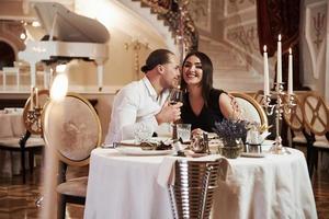 brune regarde les caméramans. un beau couple dîne romantique dans un restaurant de luxe le soir photo