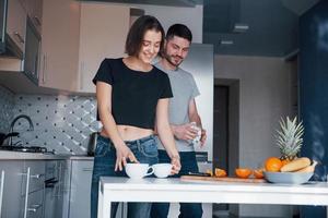 bananes et pinaple sur la table. jeune couple dans la cuisine moderne à la maison pendant leur week-end le matin photo