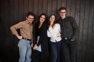 dans la salle du restaurant. la jeunesse se dresse contre un mur en bois noir. groupe d'amis qui passent du temps ensemble photo