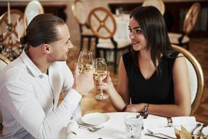 tenant des verres de champagne. un beau couple dîne romantique dans un restaurant de luxe le soir photo