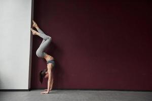 se tient à l'envers. fille avec un bon type de corps de forme physique faire des exercices dans la salle spacieuse photo