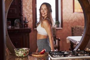 fille joyeuse. jolie jeune femme debout dans la cuisine moderne près de la cuisinière à gaz