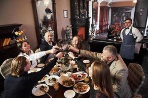 le serveur arrive. amis de la famille s'amusant dans un beau restaurant moderne de luxe photo