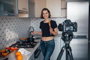 modèle heureux faisant de la nourriture. fille dans la cuisine moderne à la maison le week-end du matin photo