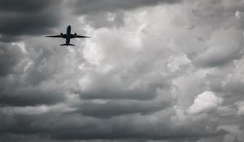 avion volant sur un ciel sombre et des nuages blancs. compagnie aérienne commerciale avec concept de destinations de rêve. concept de crise des affaires de l'aviation. vol de vacances voyage raté. transport aérien. triste voyage. photo