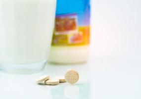 comprimés de lait aromatisé sucré et un verre de lait et bouteille de lait sur fond blanc. produits alimentaires calciques à base de lait de vache pour des os sains. photo