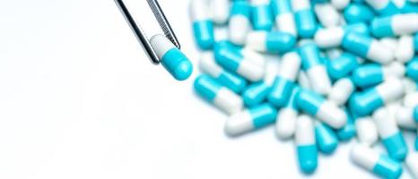 les pinces choisissent la capsule blanc-bleu du groupe de pilules de capsule. les médicaments choisissent. sélection des antibiotiques. concept de résistance aux antibiotiques. qa et qc dans le concept d'usine pharmaceutique. médicaments de choix. photo