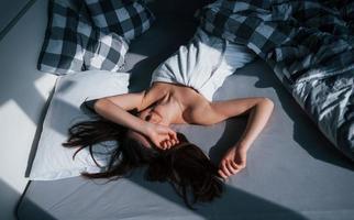 température chaude. jolie jeune femme allongée sur le lit le matin dans sa chambre photo