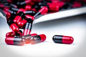 mise au point sélective des pilules de capsules rouges et noires sur le plateau de médicaments en acier inoxydable. la résistance aux antibiotiques. soins de santé mondiaux. capsules de pilules antimicrobiennes. fond de pharmacie. budgets et politiques de santé photo