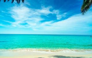 plage de sable doré au bord de la mer avec eau de mer vert émeraude et ciel bleu et nuages blancs. vacances d'été sur le concept de plage paradisiaque tropicale. ondulation des éclaboussures d'eau sur la plage de sable. ambiance estivale. photo