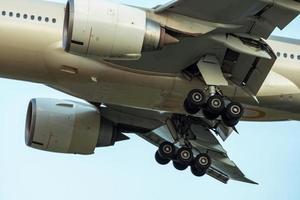 gros plan des roues en caoutchouc et du châssis de la compagnie aérienne commerciale. avion de passagers atterrissant ou décollant. génie aérospatial. avion volant sur le ciel bleu. détail du moteur de l'avion à l'atterrissage ou au décollage. photo