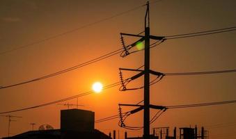 poteau électrique à haute tension et lignes de transmission dans la ville. pylônes électriques au coucher du soleil. puissance et énergie. conservation de l'énergie. tour haute tension avec câble métallique à la station de distribution. photo