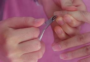 femme recevant un service de manucure des ongles par une manucure professionnelle au salon de manucure. l'esthéticienne utilise une tondeuse pour nettoyer et couper la cuticule au salon de manucure et de spa. thérapie des mains et des ongles par un thérapeute. photo