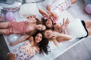 ces belles amies vous souhaitent de joyeuses fêtes. vue de dessus de jeunes filles à l'enterrement de vie de jeune fille allongées sur le canapé et levant les mains photo