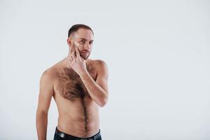 gars sérieux à l'heure du matin. homme à la poitrine nue se dresse sur fond blanc dans le studio photo