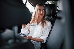 repos à l'arrière. une femme d'affaires intelligente est assise dans la voiture de luxe à l'intérieur noir photo