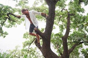 un jeune homme a grimpé à un arbre dans la forêt pour regarder autour de lui et trouver le bon chemin. le mode de vie du voyage et de la nature avec la nature photo