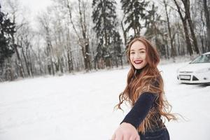 je sais où nous irons. fille aux cheveux longs va près de la forêt à l'automobile en hiver photo