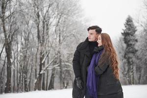 nous pouvons aller là-bas. magnifique jeune couple passe du bon temps ensemble dans la forêt enneigée photo