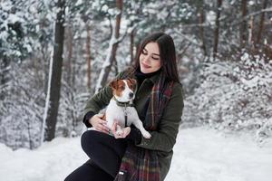 préparez-vous pour de nouvelles découvertes. brunette souriante s'amusant en marchant avec son chien dans le parc d'hiver photo