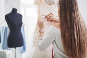vérification des détails. le processus d'essayage de la robe dans l'atelier de vêtements fabriqués à la main photo