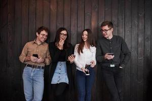 c'est en fait assez drôle. la jeunesse se dresse contre un mur en bois noir. groupe d'amis qui passent du temps ensemble photo