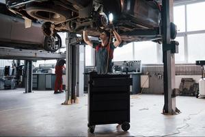 chacun fait son travail. l'homme à l'atelier en uniforme répare les pièces cassées de la voiture moderne photo