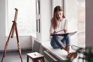 conception de l'art moderne. jeune brune dans la chambre aux murs blancs et à la lumière du jour qui vient de la fenêtre photo