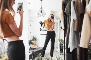 selfie dans le miroir pour donner un chèque par des amis. le processus d'essayage de la robe dans l'atelier de vêtements fabriqués à la main photo