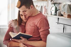 quelques informations intéressantes. joli couple lisant un livre ensemble à la maison dans la cuisine pendant la journée photo