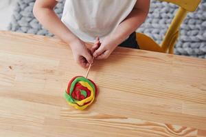 montrant le résultat du travail. enfants jouant avec de la pâte à modeler colorée sur la table en bois à la maison photo